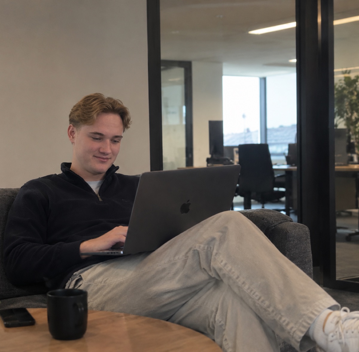 Emil Holsvik jobber på laptopen i en sofa på kontoret.